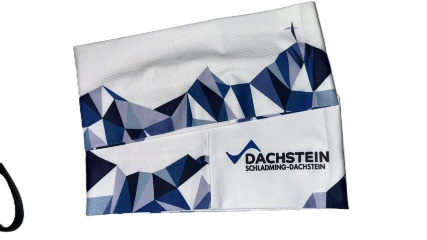 Functional fabric headband with blue geometric mountain graphic and Dachstein lettering on white background | © Planai-Hochwurzen-Bahnen Gesellschaft m.b.H.