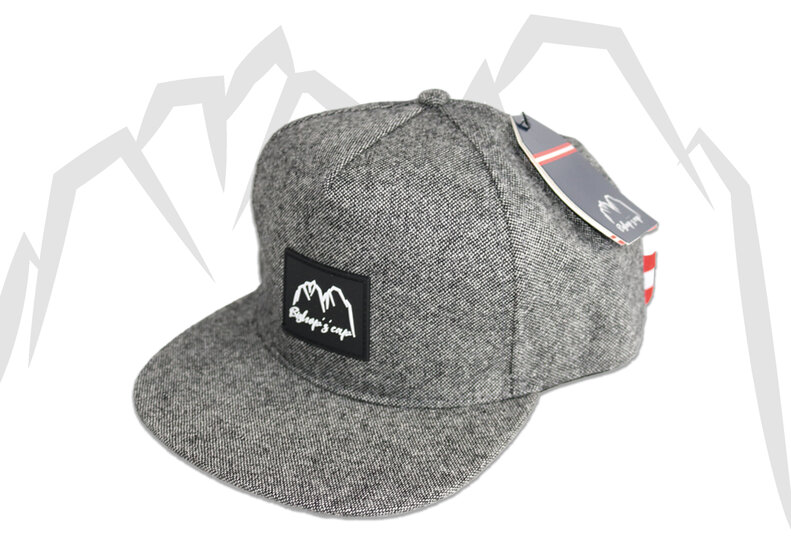 Dark grey snapback cap with flat brim and mountain logo, isolated on a light studio background. | © Bergbahnen Filzmoos GmbH
