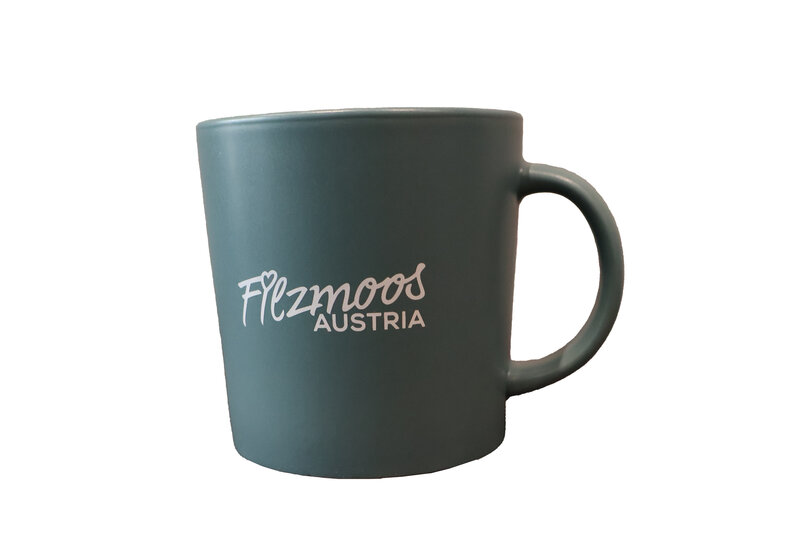 Dark green ceramic mug with Filzmoos Austria logo and handle on a light background. | © Bergbahnen Filzmoos GmbH