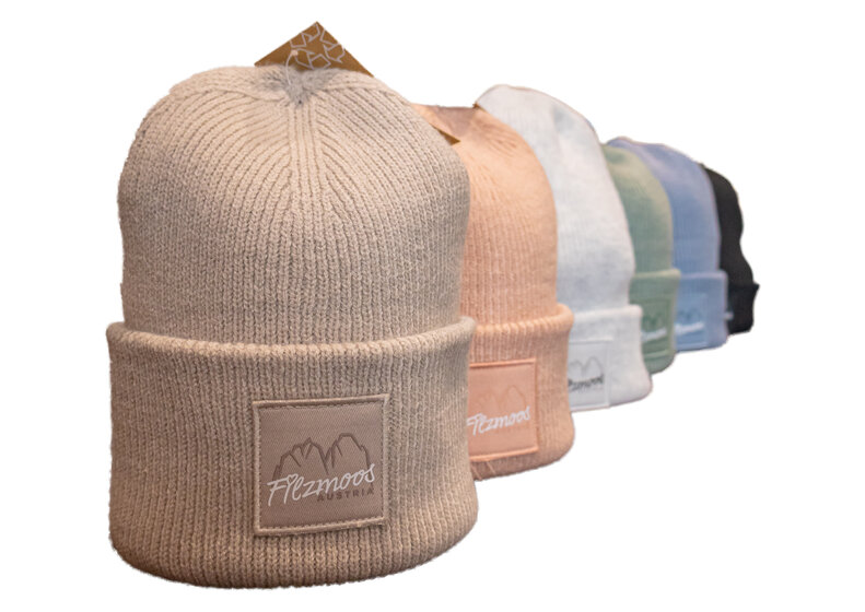 Six knitted beanies with Filzmoos mountain logo in beige, pink, white, green, blue and black. | © Bergbahnen Filzmoos GmbH