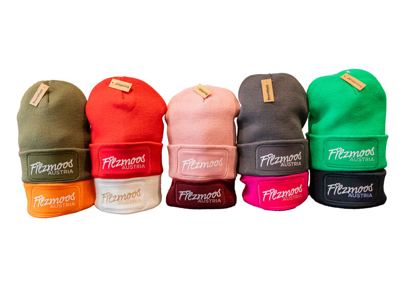 Five knitted beanies with Filzmoos Austria logo in different colours on a light background. | © Bergbahnen Filzmoos GmbH