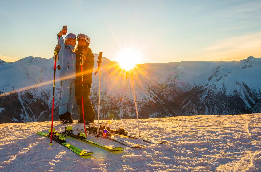 Two female skiers take a selfie at sunrise on a snowy mountain summit | © Gasteinertal Tourismus GmbH