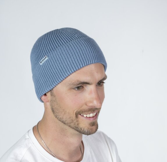 Man wearing light blue Ski amadé beanie and white shirt in front of bright backdrop | © Ski amadé GmbH