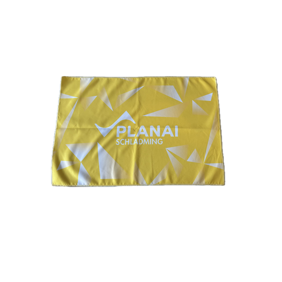 Yellow sports towel with white Planai lettering and geometric shapes, fully unfolded | © Planai-Hochwurzen-Bahnen GmbH