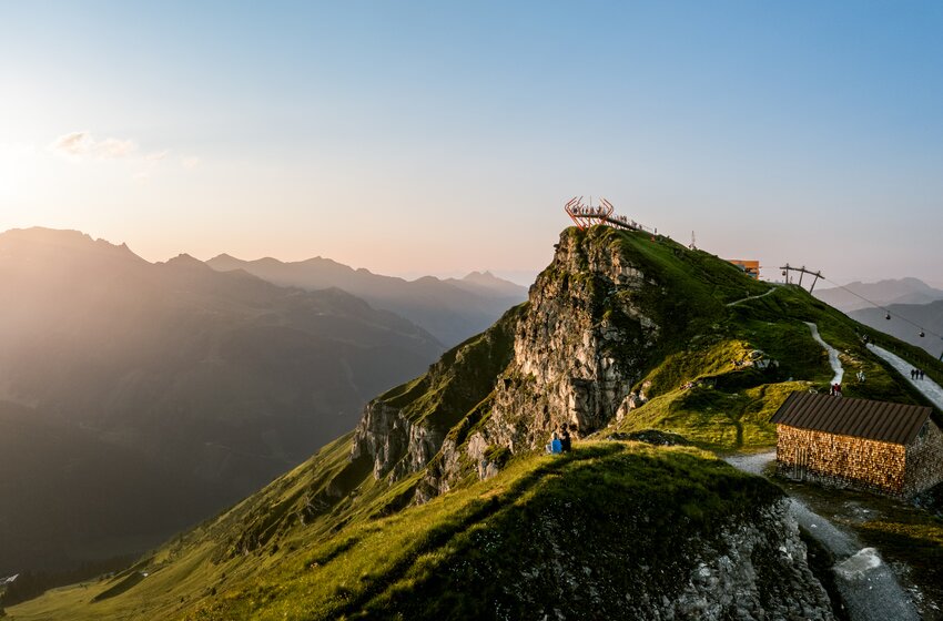 Viewing platform on rocky ridge with hiking trail, hut and view of surrounding mountains in evening light | © Gasteiner Bergbahnen AG